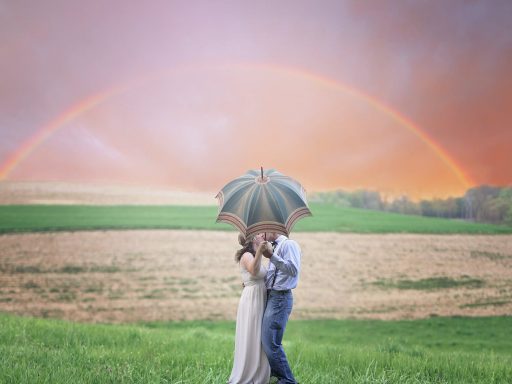 photo of couple holding umbrella while kissing