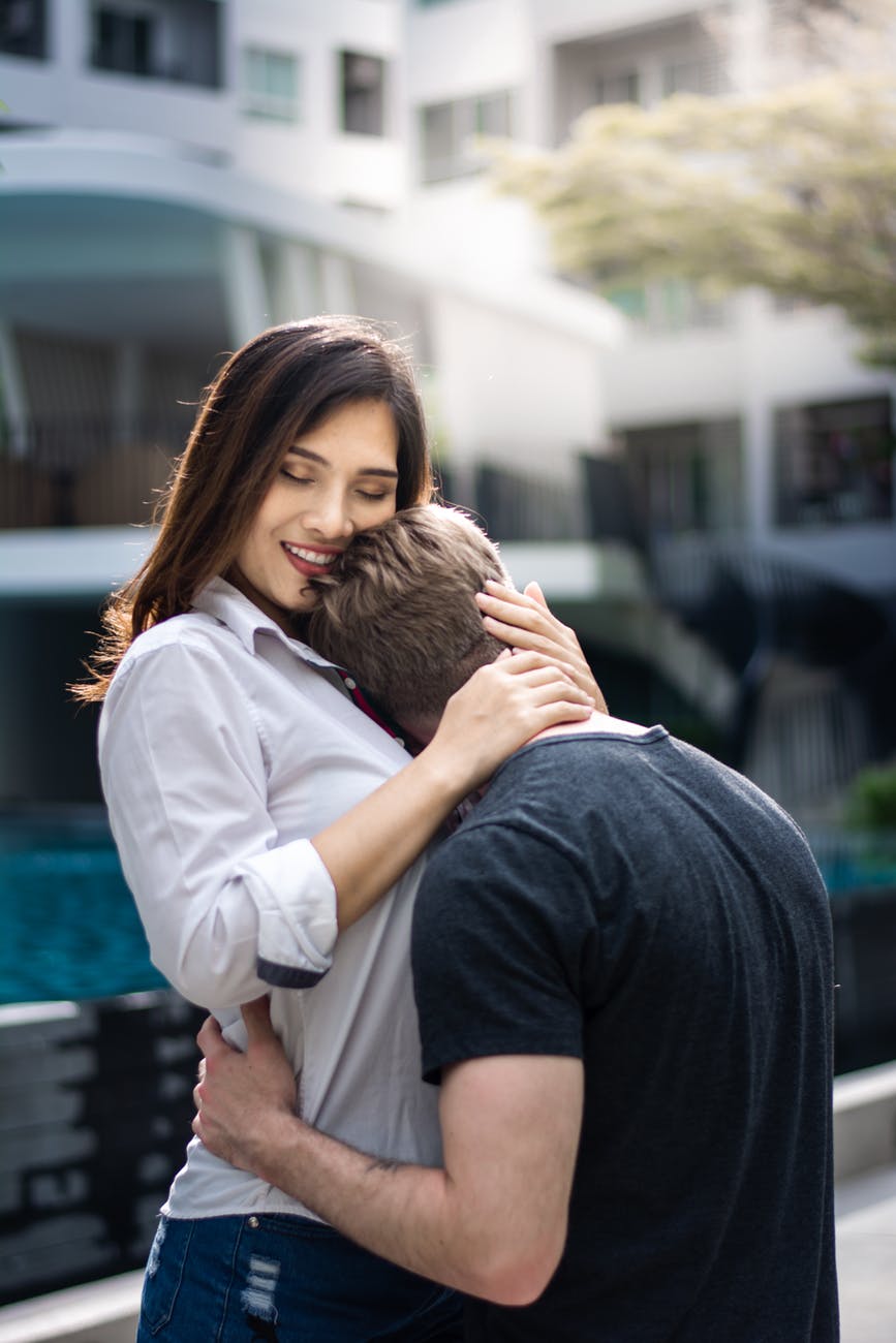 selective focus photography of woman hugging man wearing black t shirt